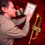 Mitgenosse on a red carpet, holding a picture of you.